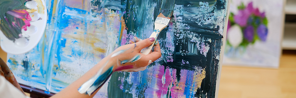Hand with a paint brush painting a canvas