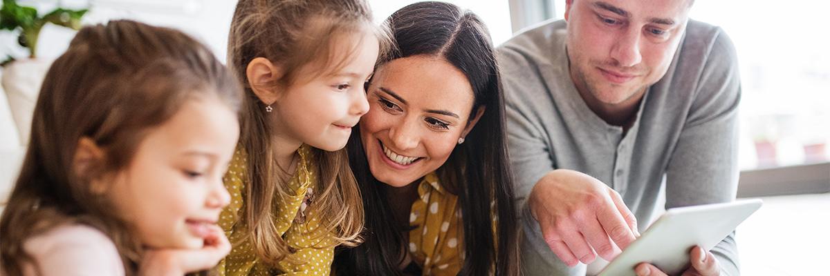 Family smiling with young kids around a tablet